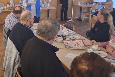 Vortrag eines Weihnachtsgedichtes von Frau Gerda Eichler Frau Eichler, stehend vor einer Tischreihe im Saal, sie hält ein Blatt Papier in der Hand von dem sie ein Gedicht vorliest.