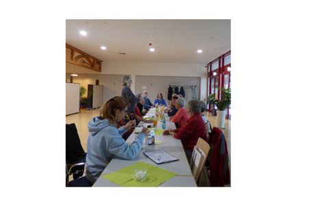 Stammtisch Liederbachhalle mehrere Personen sitzen an einer langen tafel, eine person hält eine rede