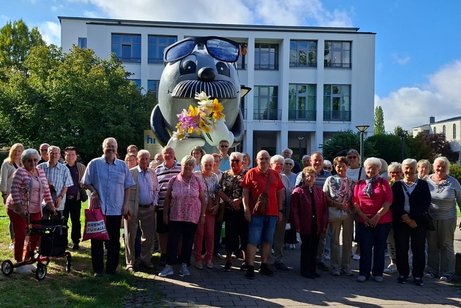 Die Teilnehmer des Ausflugs stehen zum Gruppenfoto vor dem Maskottchen des HR, dem Onkel Otto.