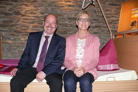 VdK-Ortsverbandsvorsitzender Alfred Strauß und Pflegeberaterin Claudia Nikel auf einem Pflegebett des Sanitätshauses Kern