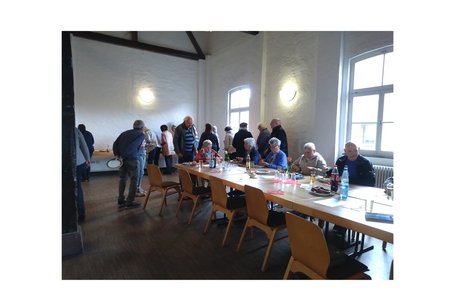 mehrere personen sitzen an tischen, andere stehen am buffet an