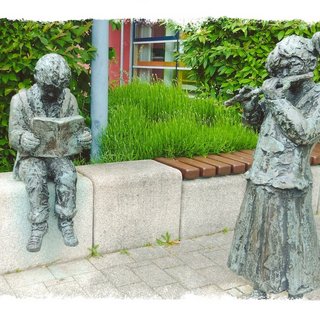 Hänsel und Gretel heißen die beiden Statuen vor der Bücherei. Ein lesender Junge und ein Mädchen das Flöte spielt. Dies sind die Arbeit des französischen Künstlers Alexandre Garcia.