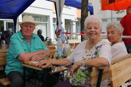 Besucher sitzen an Tischen beim Grillfest