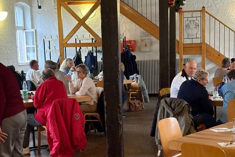 mehrere personen sitzen an tischen oder stehen und unterhalten sich