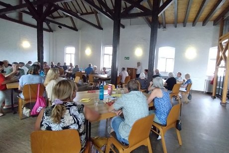 christine pfeiffer hält einen vortrag und die personen im raum hören ihr zu