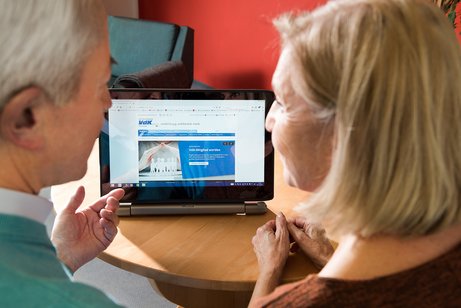 Ein &auml;lteres Paar am Computer, auf dem Bildschirm sieht man die Facebook-Seite des VdK Deutschland