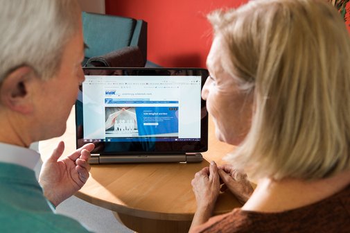 Ein &auml;lteres Paar am Computer, auf dem Bildschirm sieht man die Facebook-Seite des VdK Deutschland