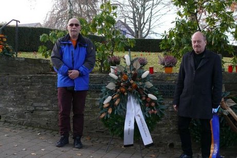 VdK-Ortsverbandsvorsitzender Alfred Strauß (rechts) und VdK- Ortsverbandskassierer Udo Zwer an der Gedenkstätte auf dem Idsteiner Friedhof mit dem Kranz des VdK-Ortsverbandes Idstein