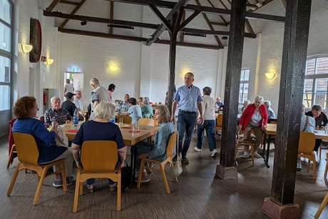 viele personen sitzend und stehend und laufend in einem raum