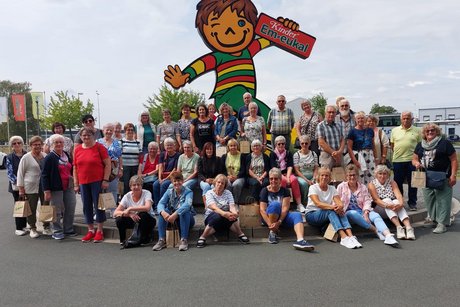 Die VdK-Besuchergruppe vor dem Maskottchen von Kinder Em-eukal.