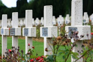 5 Grabkreuze aus Stein auf einem Friedhof.