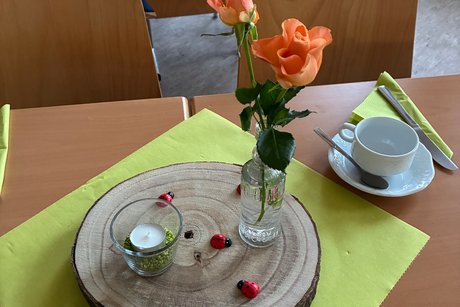 Tischdekoration mit Holzscheibe, Teelicht, gr&uuml;nen Servietten und Blumen