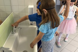 Das Bild zeigt Anette Leissner wie sie den Kindern erklärt wie man das Waschbecken und den Wasserhahn benutzt.