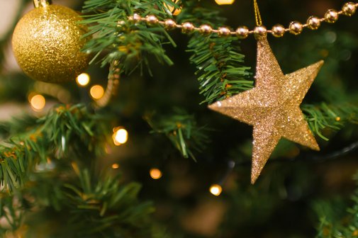 Ausschnitt eines geschm&uuml;ckten Weihnachtsbaums mit goldenen Kugeln und Sternen