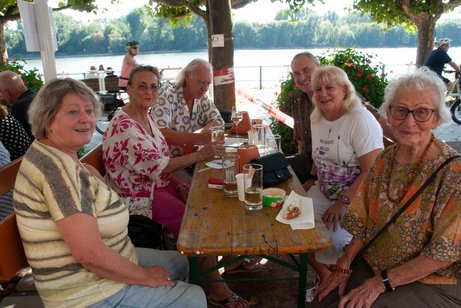 Mitglieder sitzen an Tischen und genießen ein gutes Gläschen Wein und die gesellige Atmosphäre