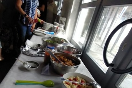 eine tafel mit salaten ist zu sehen, davor stehen mehrere personen