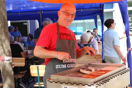 Ein Vorstandsmitglied grillt am Grillstand Würstchen und Steaks.