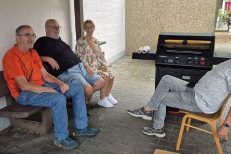 vier personen sitzen am grill und warten darauf grillen zu k&ouml;nnen