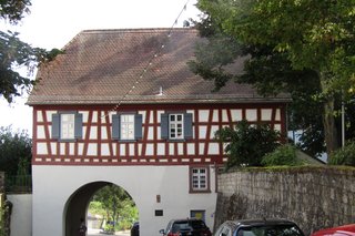 Haus mit einem Torbogen als Durchgang durch die Stadtmauer neben der Kirche