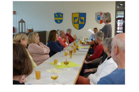 Stammtisch Liederbachhalle mehrere Personen sitzen an einer langen tafel, eine person hält eine rede