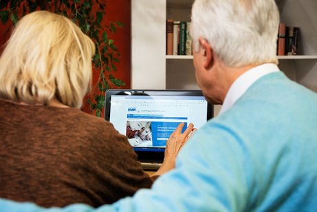 Ein &auml;lteres Paar am Computer, auf dem Bildschirm sieht man die Facebook-Seite des VdK Deutschland