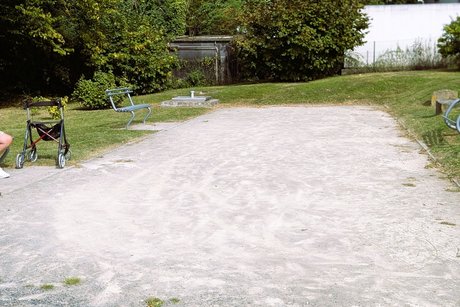 Unser Boule- Platz in der Pommernstraße Ein Sand-/Kiesplatz hinter einem Spielplatz mit Bänken und Rasenfläche drumherum, der als Bouleplatz genutzt werden kann.