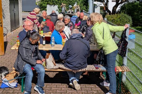 Die Teilnehmer des Grillfestes sitzen an Tischen und unterhalten sich angeregt