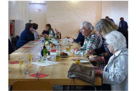mehrere personen sitzen an tischen und unterhalten sich