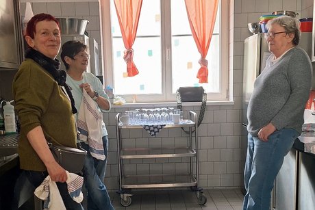 Drei Frauen mit K&uuml;chentuch stehen in einer K&uuml;che