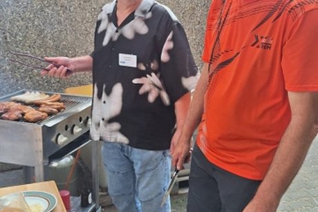 2 männer stehen vor einem grill
