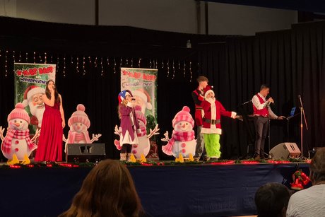 Eine Gruppe Kinder in Weihnachts-Outfits singt f&uuml;r das Publikum