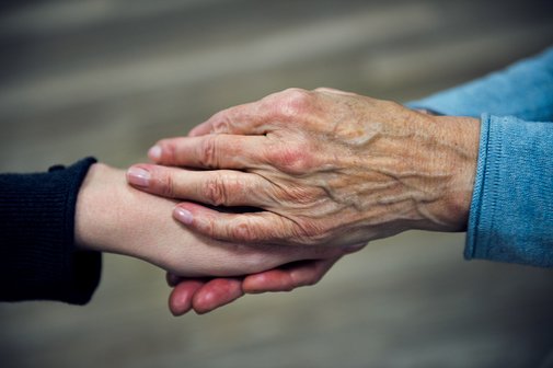 Die Hand einer &auml;lteren Frau h&auml;lt die Hand einer j&uuml;ngeren Frau in einer tr&ouml;stenden Geste.