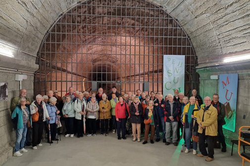 Teilnehmer im offenen Bunkerbereich Teilnehmer stehen vor großem Stahlgitter