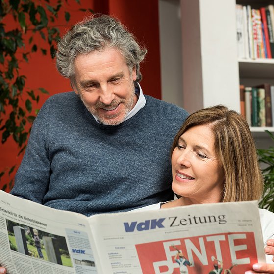 Paar liest die VdK-Zeitung Ein Mann und eine Frau schauen gemeinsam in die VdK-Zeitung, auf der Titelseite geht es um das Thema Rente