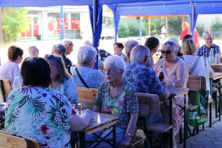 Mitglieder sitzen an Tischen beim Grillnachmittag