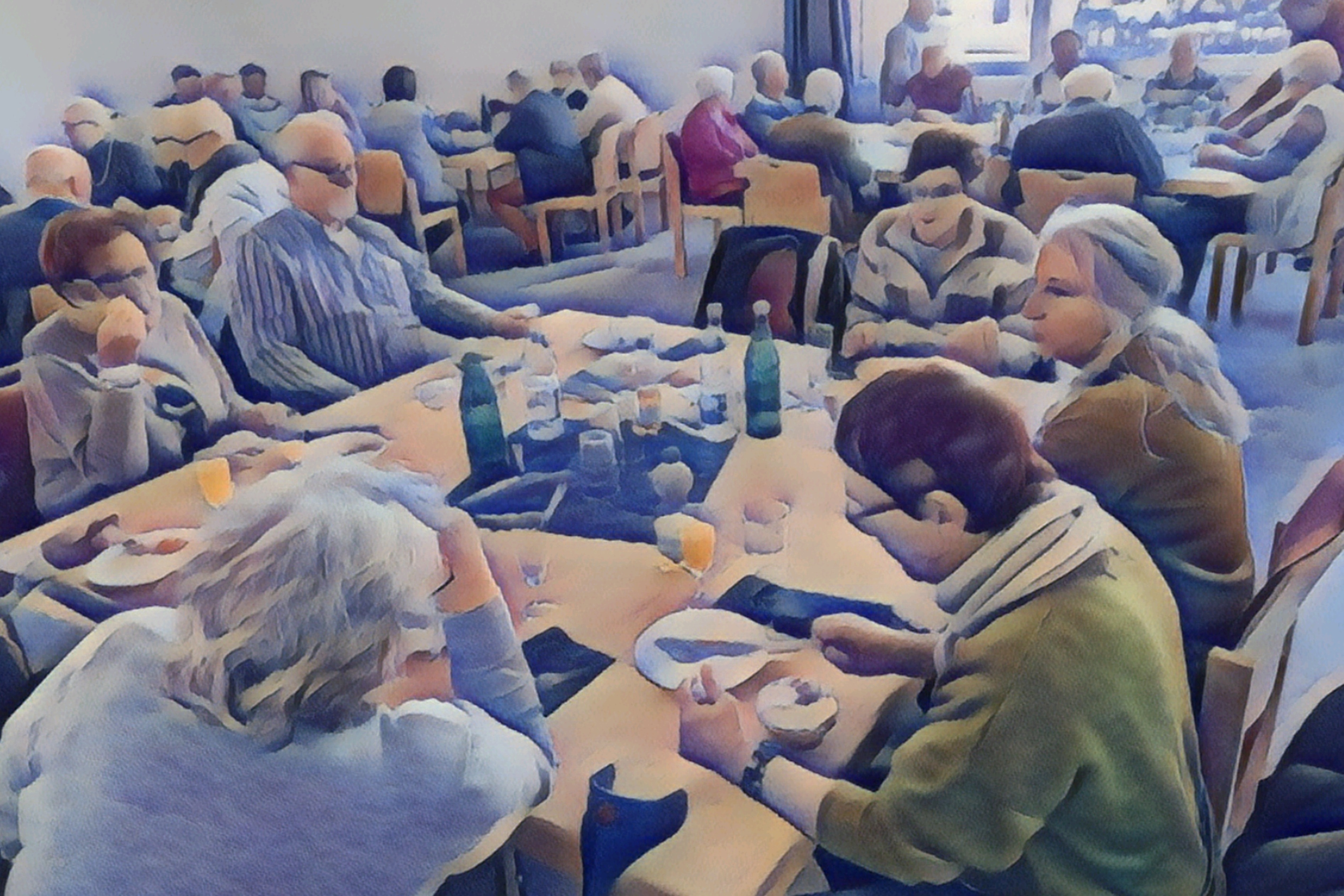 Ein Raum mit mehreren Tischen an denen eine Vielzahl von meist älteren Menschen sitzen, sie haben Getränke und etwas zu essen auf den Tischen stehen.