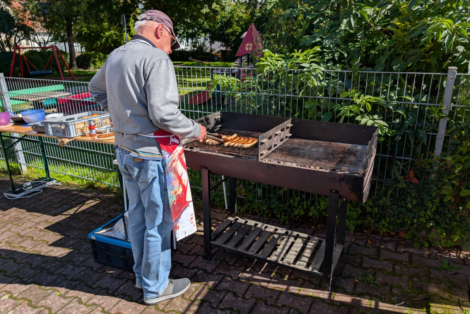 Herr Lewandowski steht vor dem Grill und kümmert sich um die Bratwürste