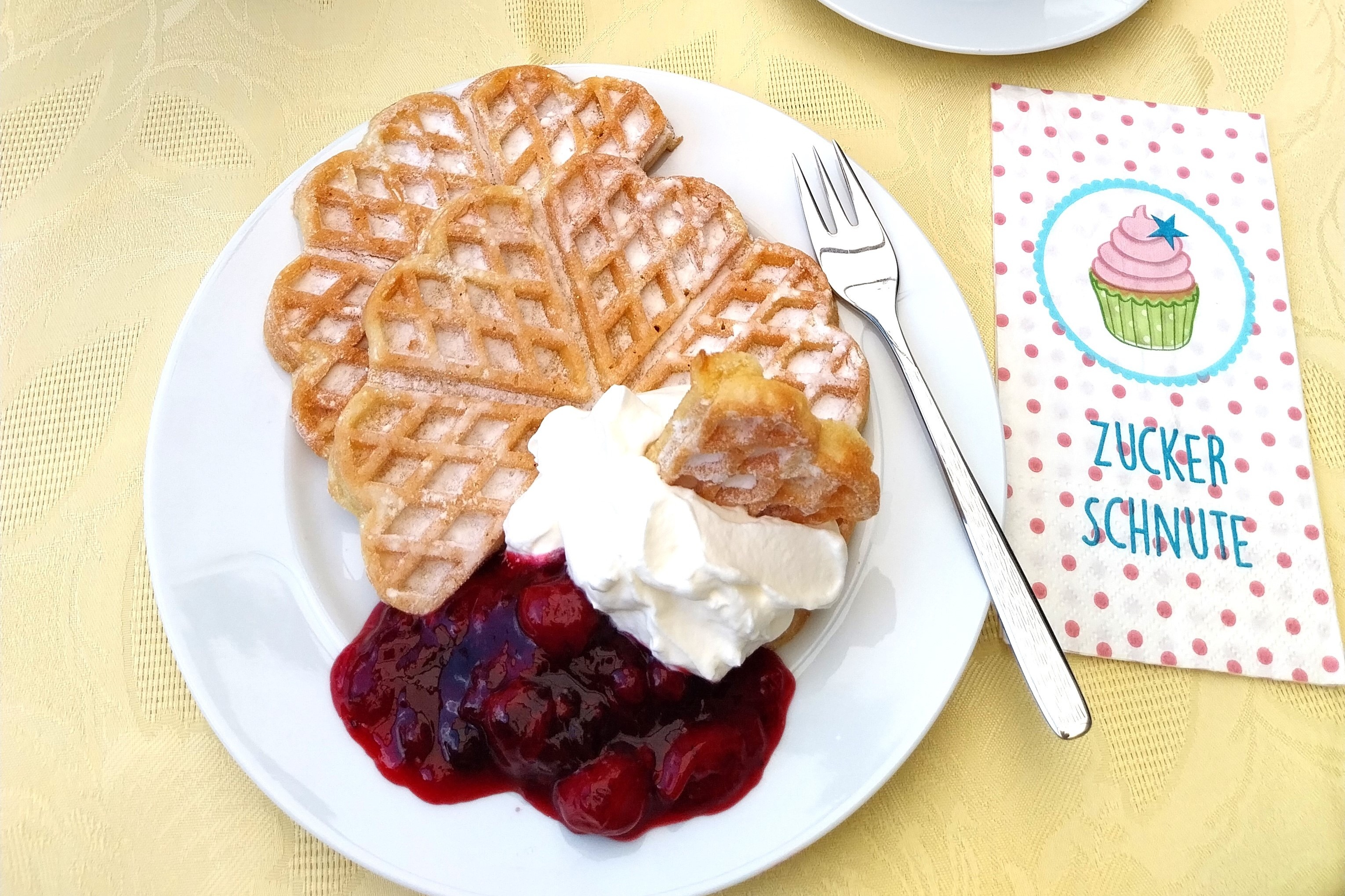 Teller mit Waffel, Sahne, Kirschen