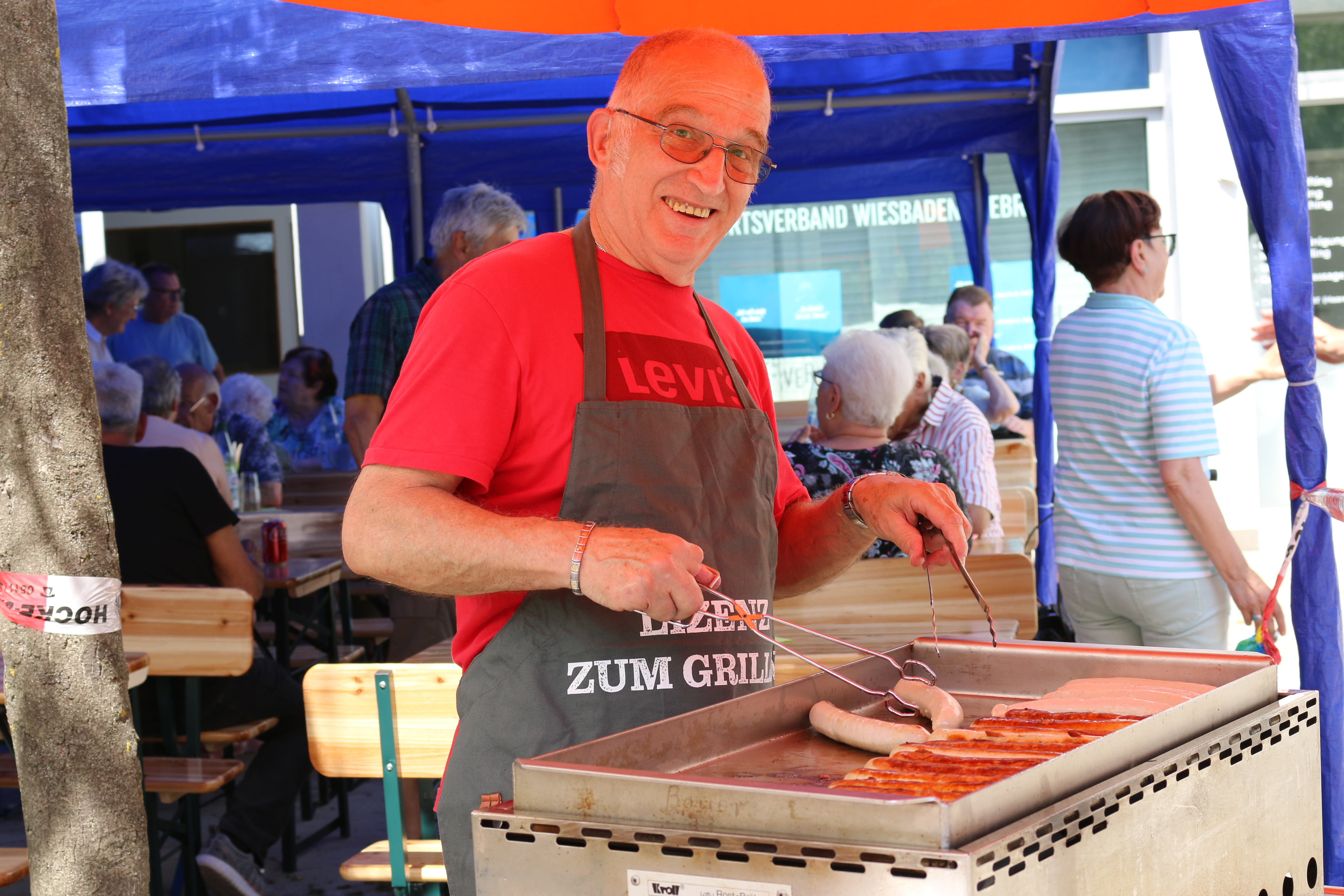 Ein Vorstandsmitglied grillt am Grillstand Würstchen und Steaks.