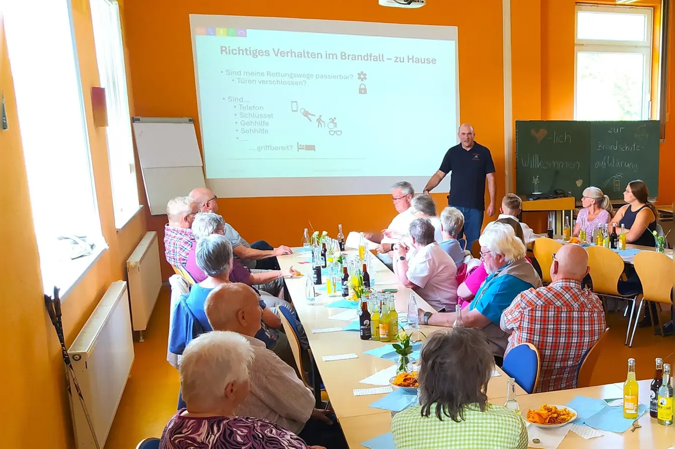 Veranstaltungsfoto, mehrere Personen im Versammlungsraum vor einer Powerpointpr&auml;sentation