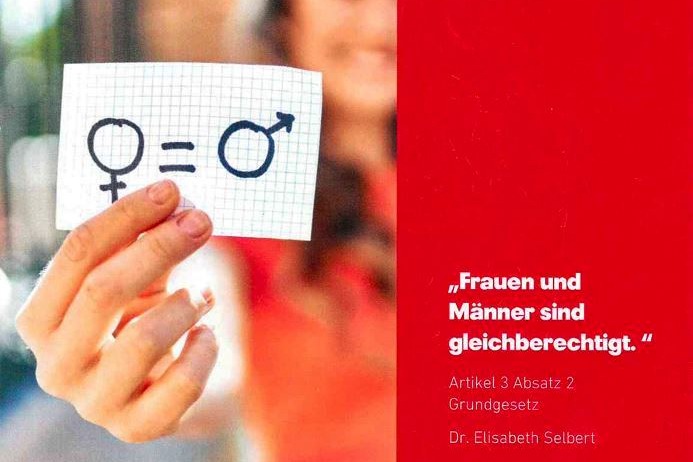 Eine Hand zeigt die Karte: Männer und Frauen sind gleichberechtigt.