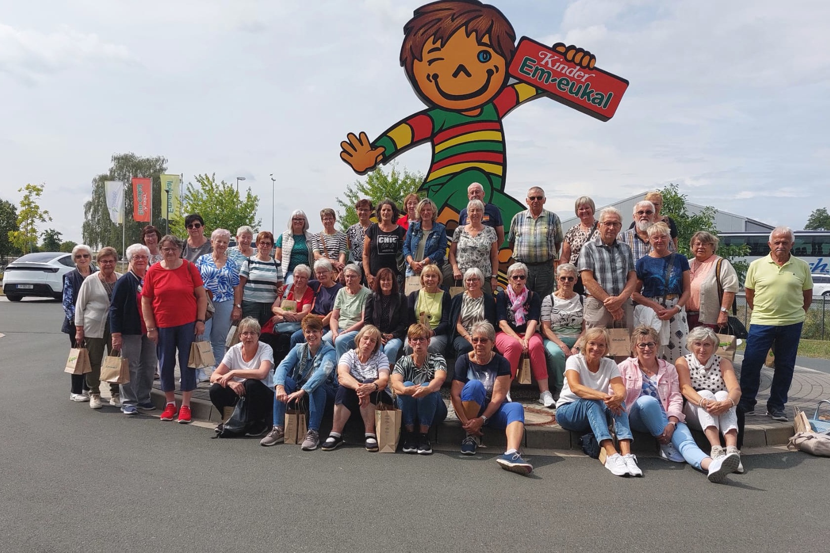 Die VdK-Besuchergruppe vor dem Maskottchen von Kinder Em-eukal.