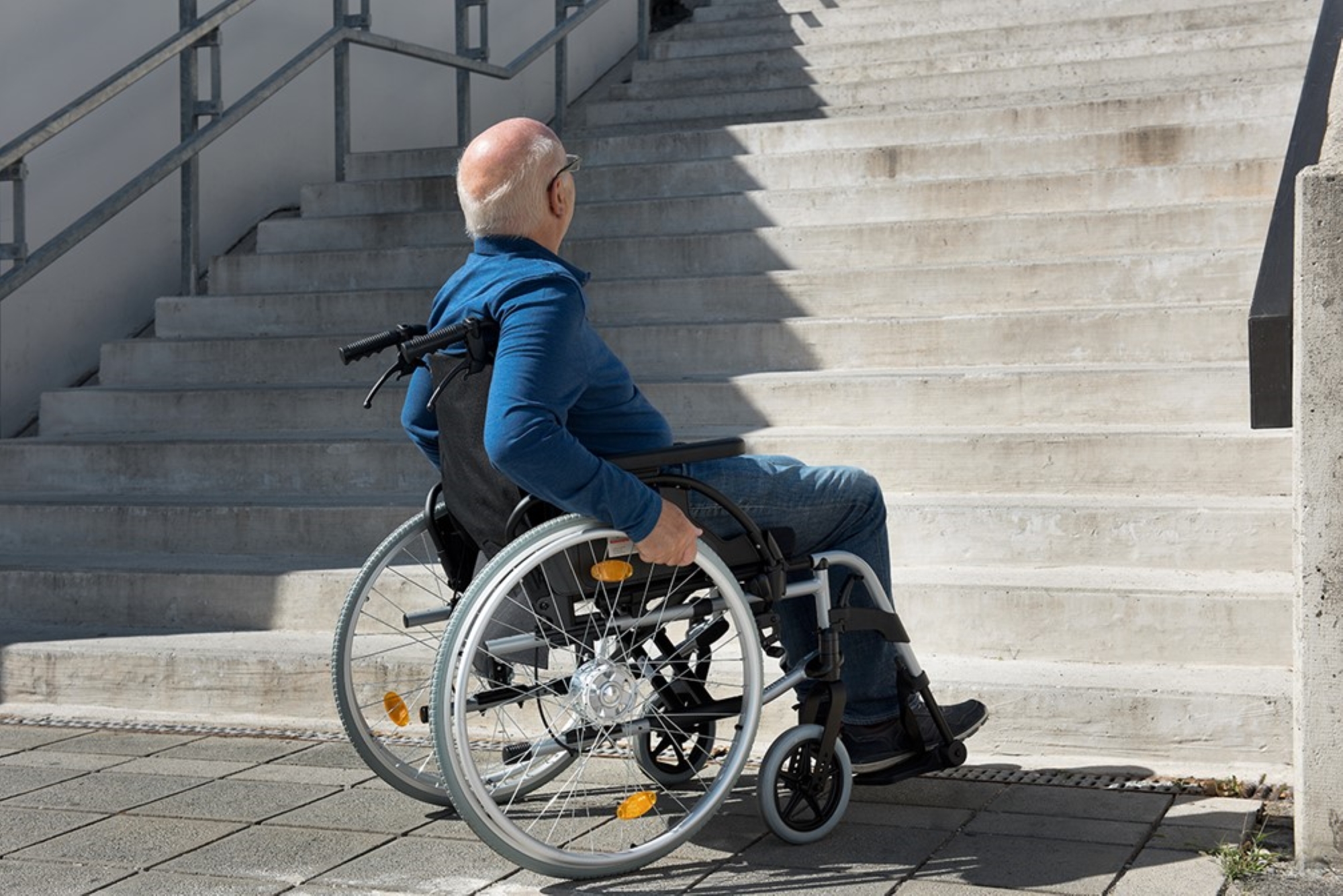 Rollstuhlfahrer vor Treppe