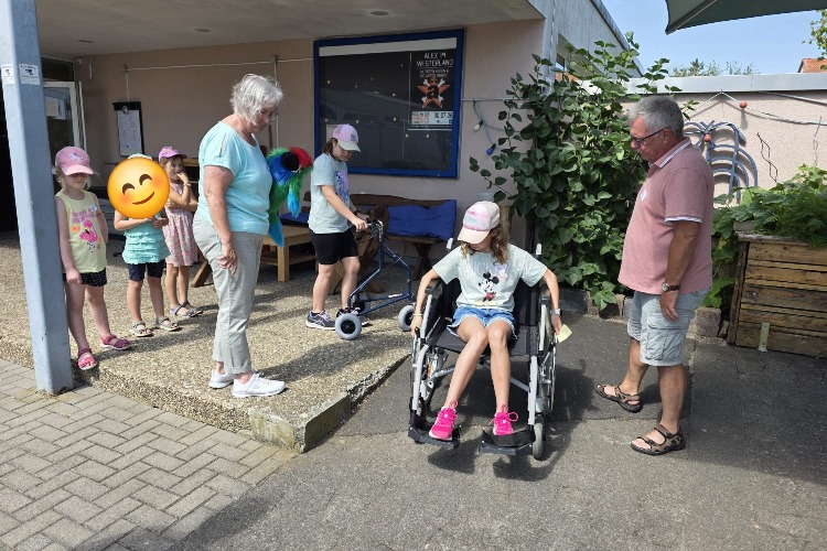 Die Kinder mit Betreuern in Aktion die 2 Betreuer S. Ewe und H. Reichmann und die Kindern üben den Umgang mit Hilfsmittel wie Rollator und Rollstuhl