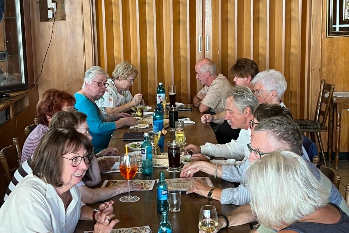 Auf dem Bild sieht man eine gesellige Runde beim VdK-Babbelabend. Mehrere Teilnehmerinnen und Teilnehmer sitzen gemeinsam an einem langen Tisch in gemütlicher Atmosphäre. Es wird miteinander gesprochen, gelacht und gegessen; auf dem Tisch stehen Getränke und Speisekarten. Die Aufnahme vermittelt besonders schön die offene und freundschaftliche Stimmung der Runde – genau das, was einen Babbelabend ausmacht: zusammenkommen, sich austauschen, viel Spaß haben und voneinander lernen.