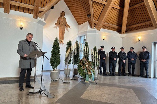 Gedenkrede Herr Bürgermeister Ball Bürgermeister Ball hält seine Rede zum Volkstrauertag. Im Hintergrund ist der Kranz und die Feuerwehr zu sehen.